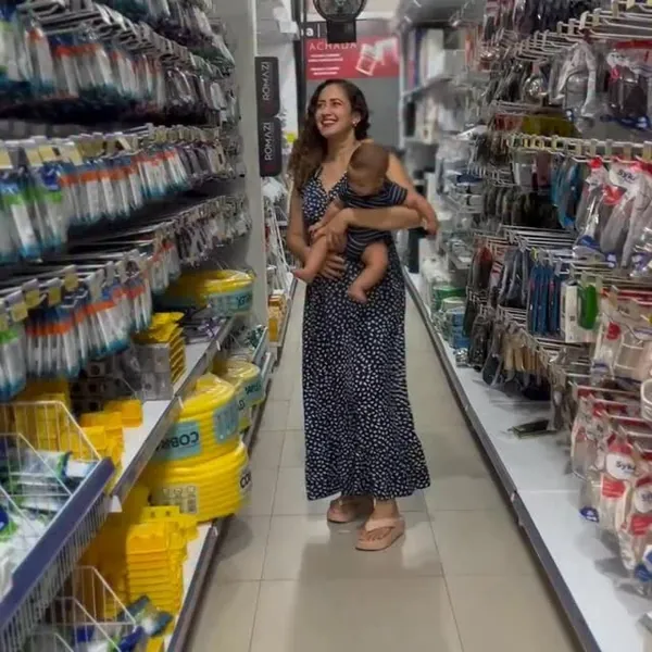 Cliente com bebê no colo passeando pelo corredor de hidráulica da Comercial Lucena